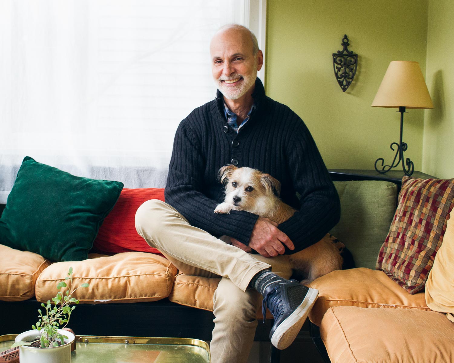Portrait of Dave Cesana sitting on couch with dog